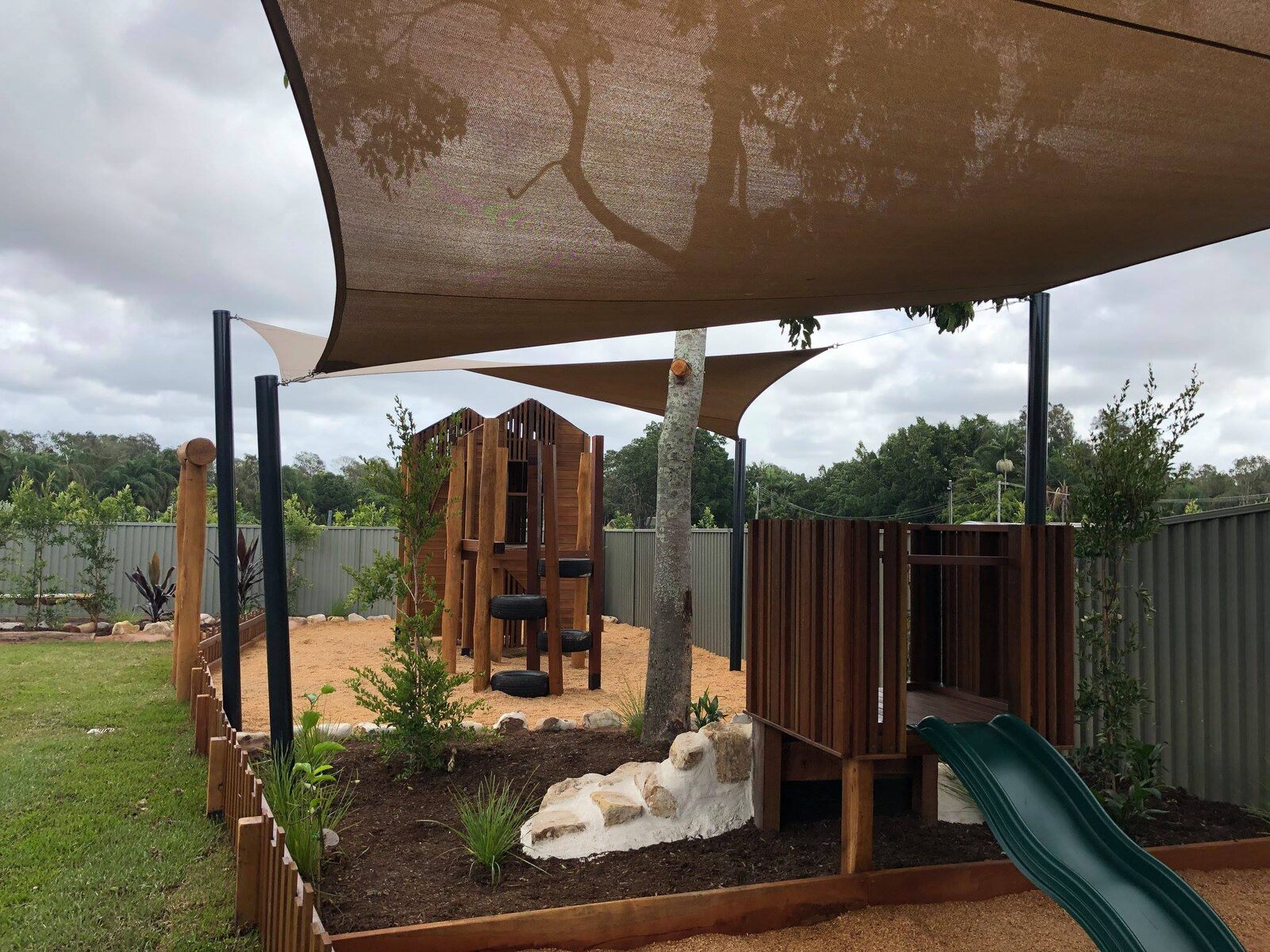 Wooden treehouse and shaded playground with native landscaping